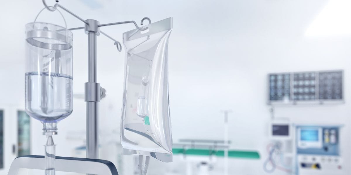 A hospital room featuring IV bags, medical equipment, and a bed, indicating a patient care environment.