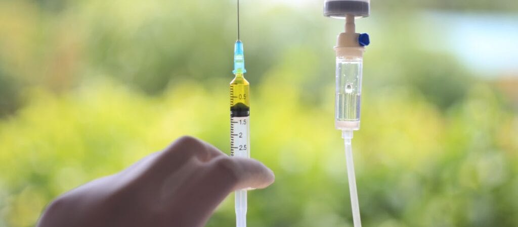 A person holding a syringe and needle, preparing for an injection.