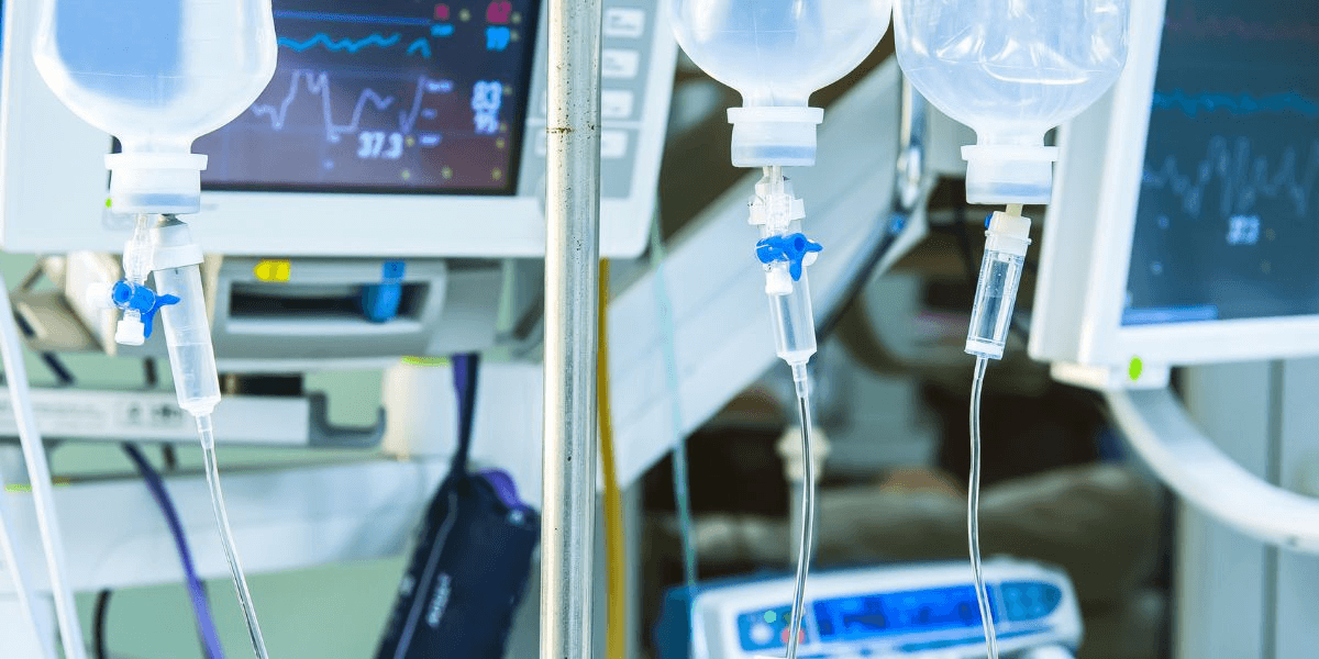 A hospital room featuring IV stands, medical monitors, and a bed, indicating a patient care environment.