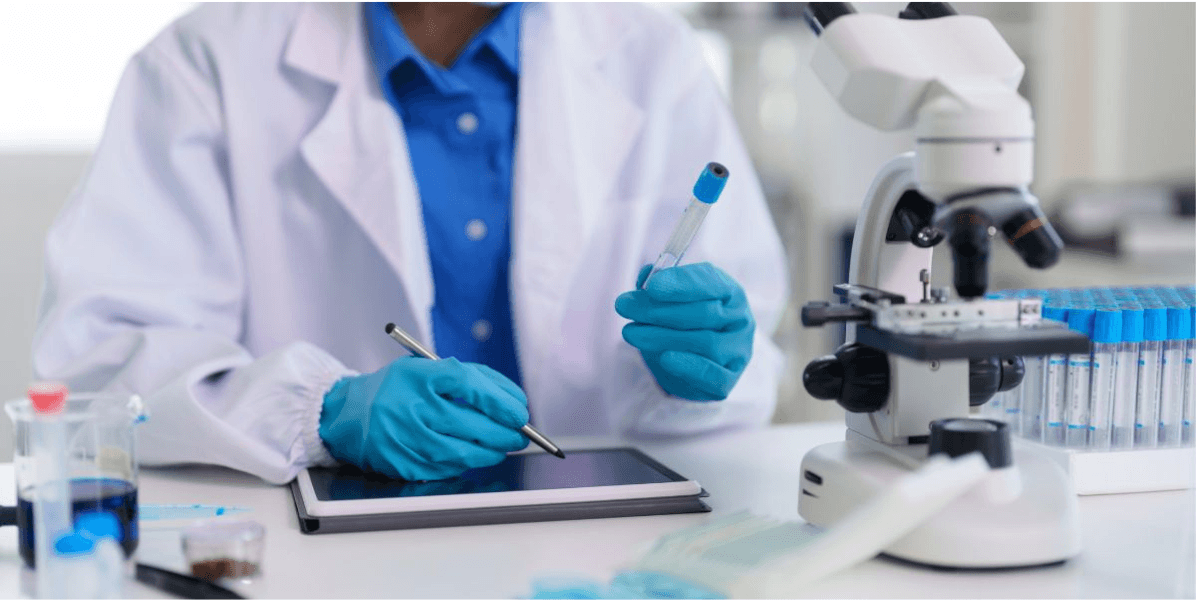 A person in a lab coat focused on a tablet, engaged in research or data analysis in a laboratory setting.