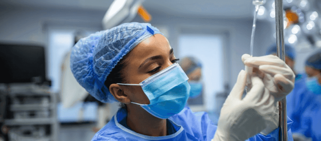 A female surgeon wearing a surgical gown and mask, focused and ready for a procedure in an operating room.