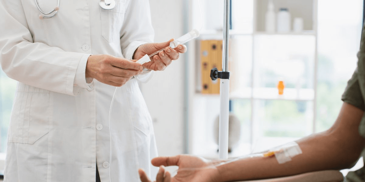 A doctor administers a blood transfusion to a patient in a clinical setting.