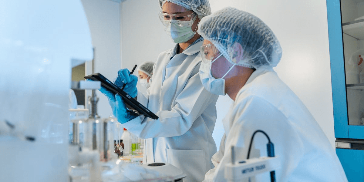 Two individuals in lab coats collaborating on a tablet in a laboratory setting.